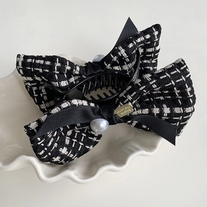 Macro detail of tweed bow hair claw with faux pearl and houndstooth texture