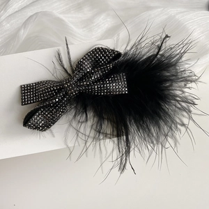 Close-up of black ostrich feather hair clip with sparkling rhinestones on display card
