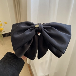 Détail du grand nœud papillon en satin noir avec plaque dorée et perles scintillantes