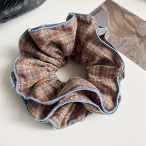 Detailed texture of blue-brown plaid hair scrunchie with light blue pleated edges