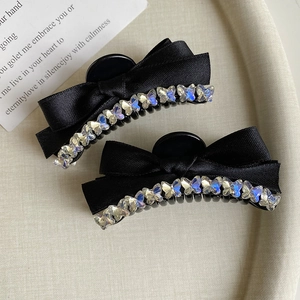 Close-up of black satin bow hair clips with iridescent butterfly rhinestones on a tray