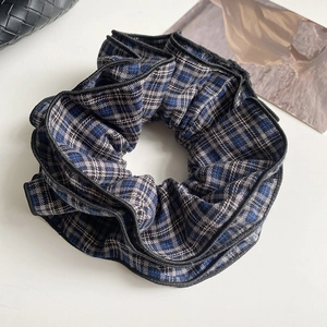 Detailed close-up of dark plaid fabric hair scrunchie with layered wave edge texture