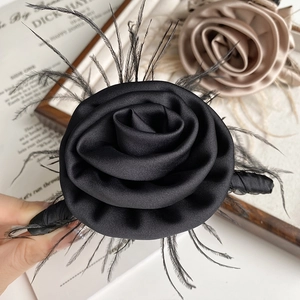 Macro detail of elegant black satin rose hair claw with lightweight feather accents