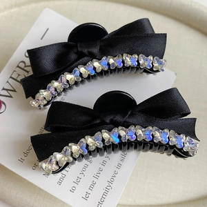 Close-up of black satin ribbon bow hair clips with shimmering butterfly rhinestones