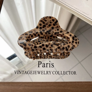 Close-up of leopard print hair claw clip made of amber acetate on a mirrored surface