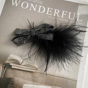 Detail of elegant black ostrich feather hair clip with sparkling rhinestone bow design