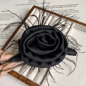 Close-up of elegant black satin rose hair claw with delicate feather details