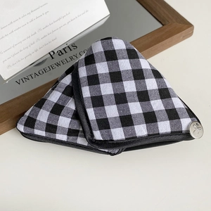 Detail of a black and white checkered fabric hair claw clip with a silver bow metal logo