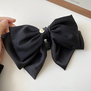 Détail du nœud papillon en satin noir élégant avec strass brillants et emblème doré