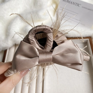 Detail view of large champagne satin bow hair claw clip with delicate feather trim