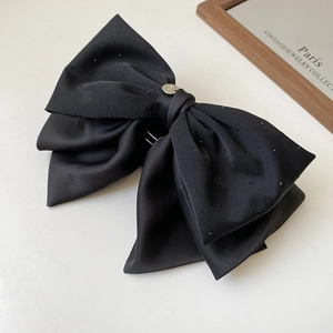 Détail d'une grande pince à cheveux nœud en satin noir ornée de strass étincelants