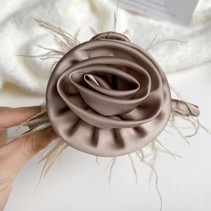 Detailed view of champagne rose hair claw clip with satin petals and soft feather accents