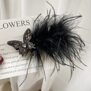 Elegant black feather hair clip with crystal butterfly detail on vintage script card
