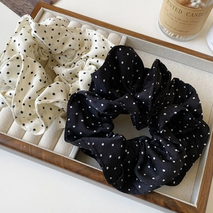 Französisches Set aus gepunkteten Satin-Haargummis in Schwarz und Weiß auf Holztablett