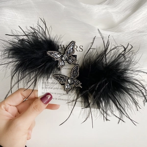 Detailed close-up of a luxury black feather butterfly hair clip with sparkling rhinestones