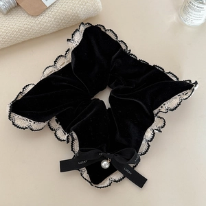Detail eines Samt-Lace-Scrunchies mit Lucky-Schleife und künstlichem Perlenanhänger