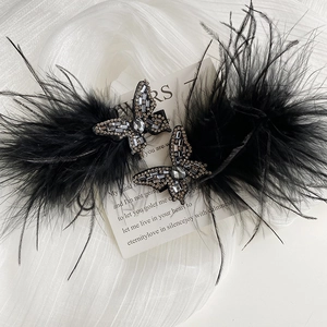 Close-up detail of butterfly rhinestone hair clips with elegant black feathers