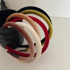 Macro shot of six velvet padded headbands in various colors with handmade fabric labels