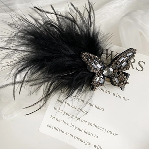 Detailed macro of black feather hair clip with sparkling rhinestone bow on elegant fabric