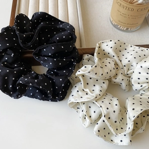 Detailansicht eleganter schwarz-weißer Polka-Dot-Haargummis auf einem schönen Holztablett
