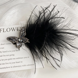 Detailed macro view of a black feather hair clip with sparkling rhinestone butterfly