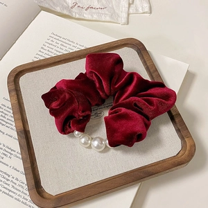 Macro shot of burgundy velvet scrunchie with elegant white faux pearl decorations