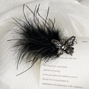 Detailed view of elegant black feather butterfly hair clip with sparkling rhinestones