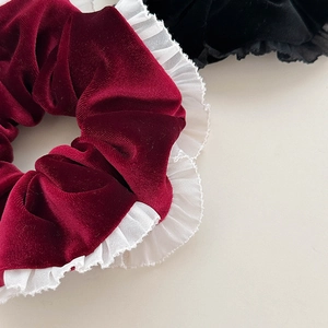 Détail d'un chouchou en velours bordeaux avec bordure en dentelle blanche élégante
