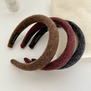 Detail of three thick textured autumn headbands in brown, burgundy, and dark grey tones
