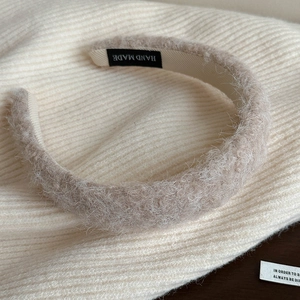 Détail du serre-tête fait main en laine d'agneau pelucheuse beige café avec étiquette interne