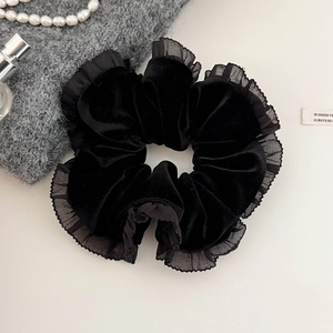 Gros plan sur chouchou en velours noir avec bordure en dentelle et décor de perles
