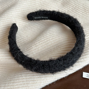 Vue détaillée du serre-tête en peluche noire avec étiquette faite à la main