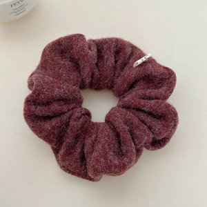 Detailed view of a deep red wool texture scrunchie with a small designer woven label