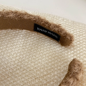 Détail de la texture d'un serre-tête en peluche marron avec étiquette faite main
