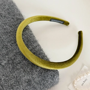 Detail of olive green velvet headband with handmade label on knitted fabric