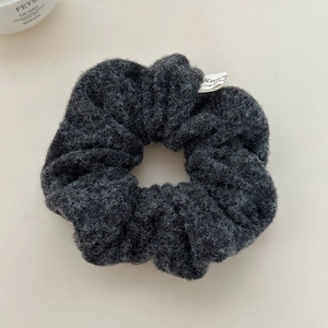 Detail of dark grey bouclé scrunchie with soft fluffy texture and white woven label