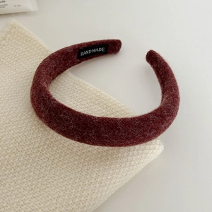 Detail of burgundy textured thick headband with handmade label on knitted background