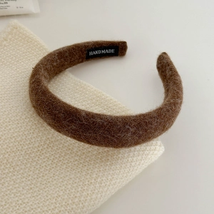 Detail of dark coffee fuzzy knit headband featuring a handmade label and soft texture