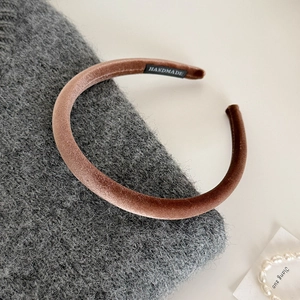Detail of brown velvet headband with handmade label on grey knit texture background