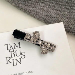Close-up of a luxury black velvet hair clip featuring a shimmering rhinestone bow detail