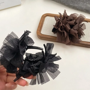 Dettaglio di grandi mollette per capelli con fiocco in tulle nei colori nero e caffè