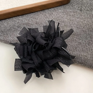 Dettaglio del fermaglio per capelli a fiore nero in tulle scintillante e chiffon a pieghe
