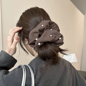 Détail du chouchou en satin marron café avec perles blanches sur cheveux de mannequin
