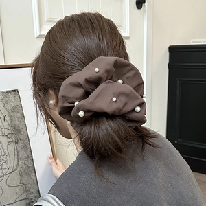 Détail d'un chouchou en tissu marron avec perles blanches porté en queue de cheval