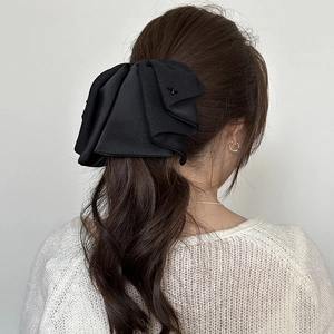 Close-up of elegant black layered satin bow hair clip on a model with long curly hair