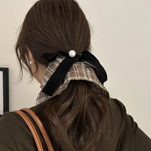 Detail of checkered bow hair scrunchie with soft velvet ribbon and elegant faux pearl
