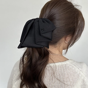 Elegant large black multilayer bow hair claw clip worn on model with wavy hair