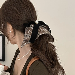 Detail of checkered bow scrunchie with pearl accent on a low ponytail hair style