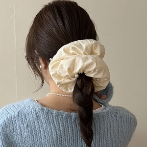 Chouchou élégant en tissu crème avec perles sur une coiffure de tresse française