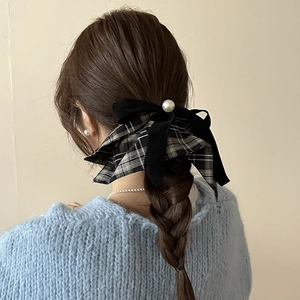Detail of retro bow hair tie with pearl accent on braid, velvet and plaid textures